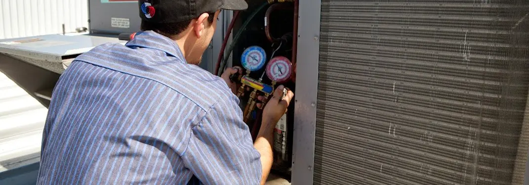 HVAC technician servicing a condenser unit in Wyoming